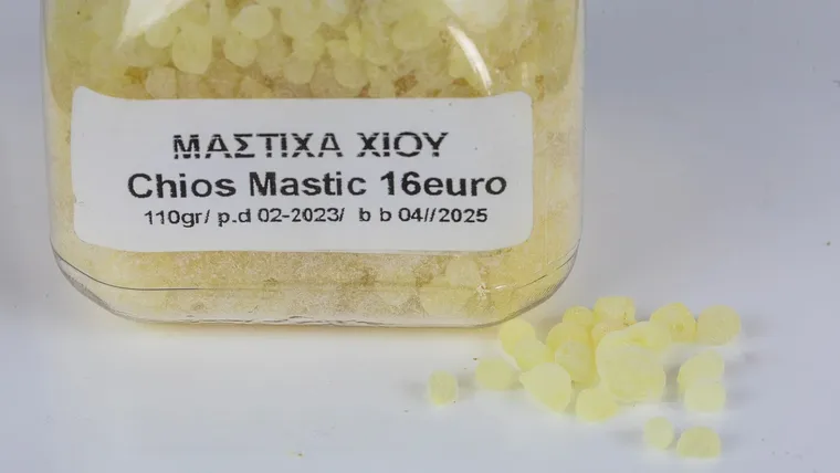 Chios mastic resin displayed in a jar with loose pieces beside it.