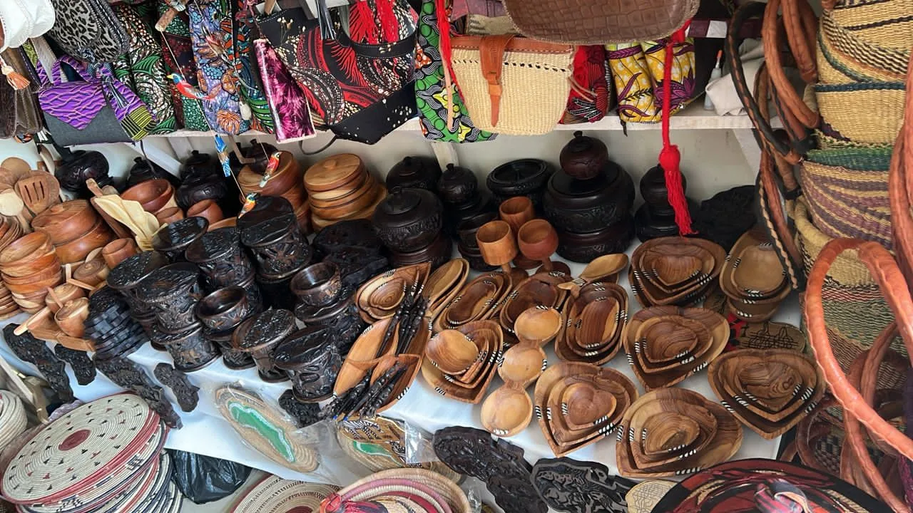 Handcrafted wooden bowls, trays, cups and spoons alongside woven baskets at Abuja Arts and Culture Village.
