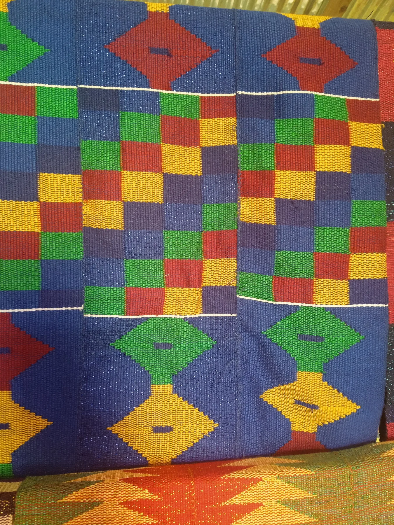 A close view of Tafi kente cloth with vivid red, blue, yellow and green geometric patterns.