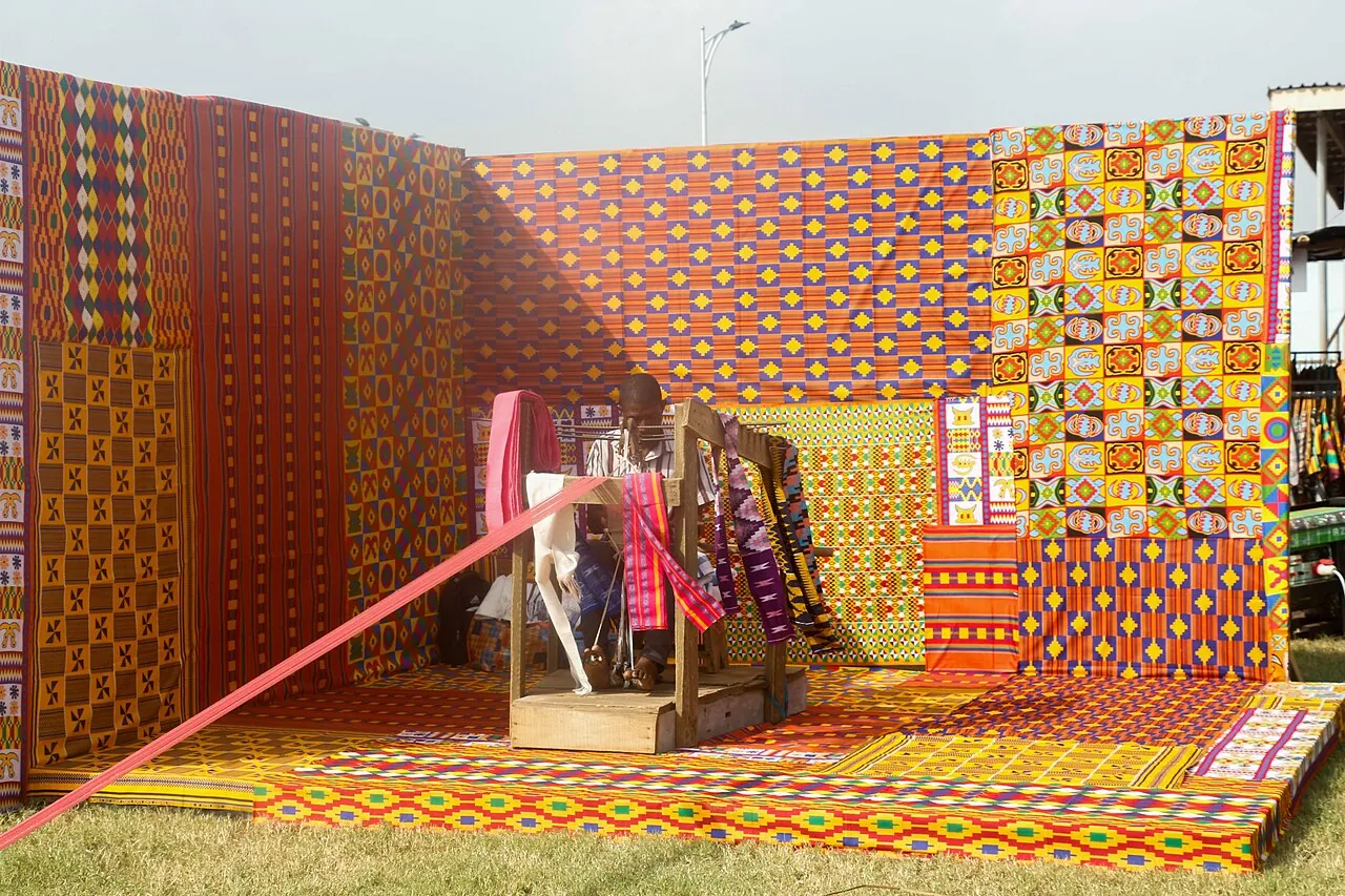 Techniques A Ghanaian weaver works on colourful kente cloth at a wooden loom.
